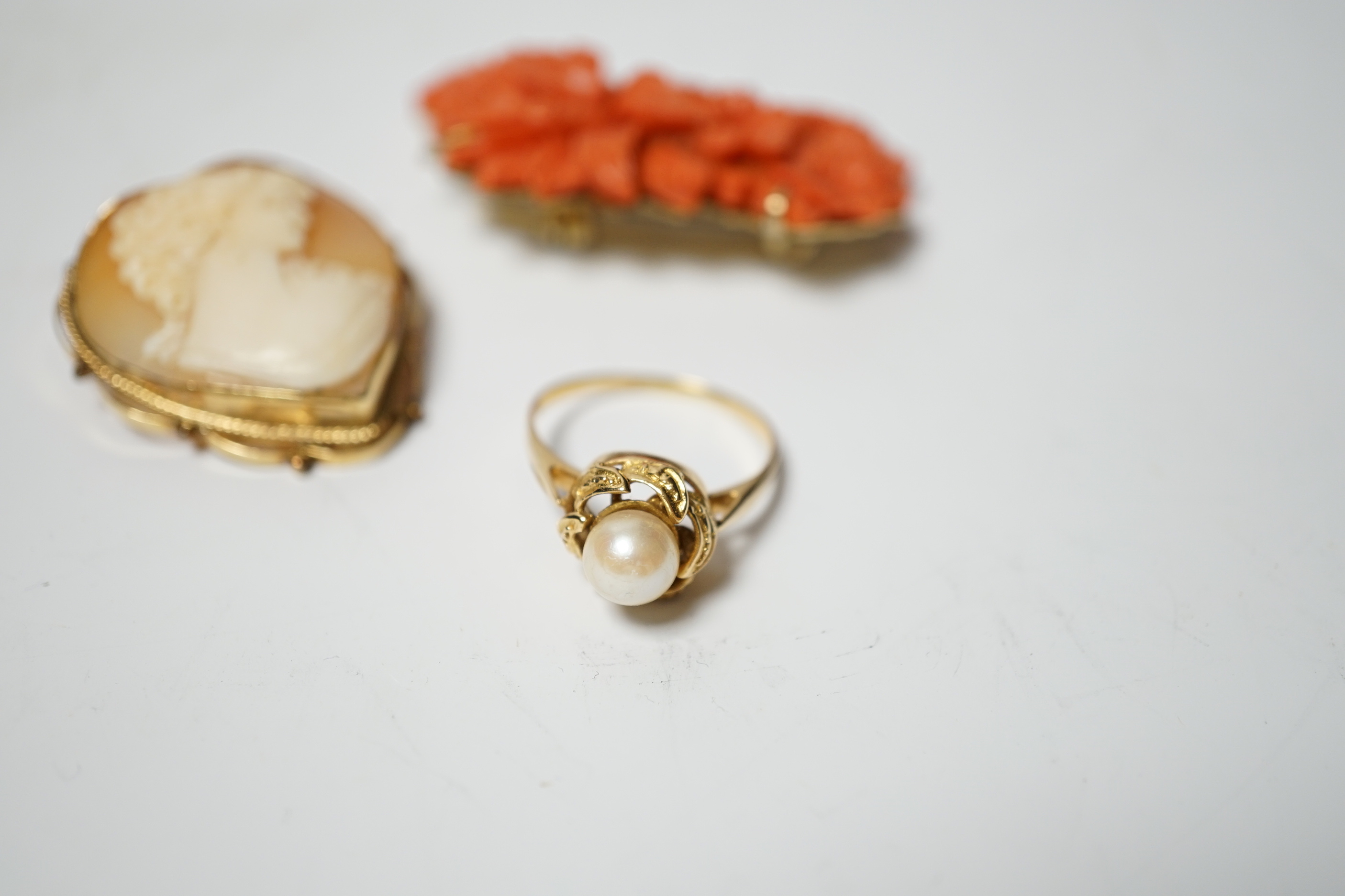 A 14k mounted heart shaped cameo shell pendant brooch, 33mm, a yellow metal and single stone cultured pearl set ring and a coral brooch.